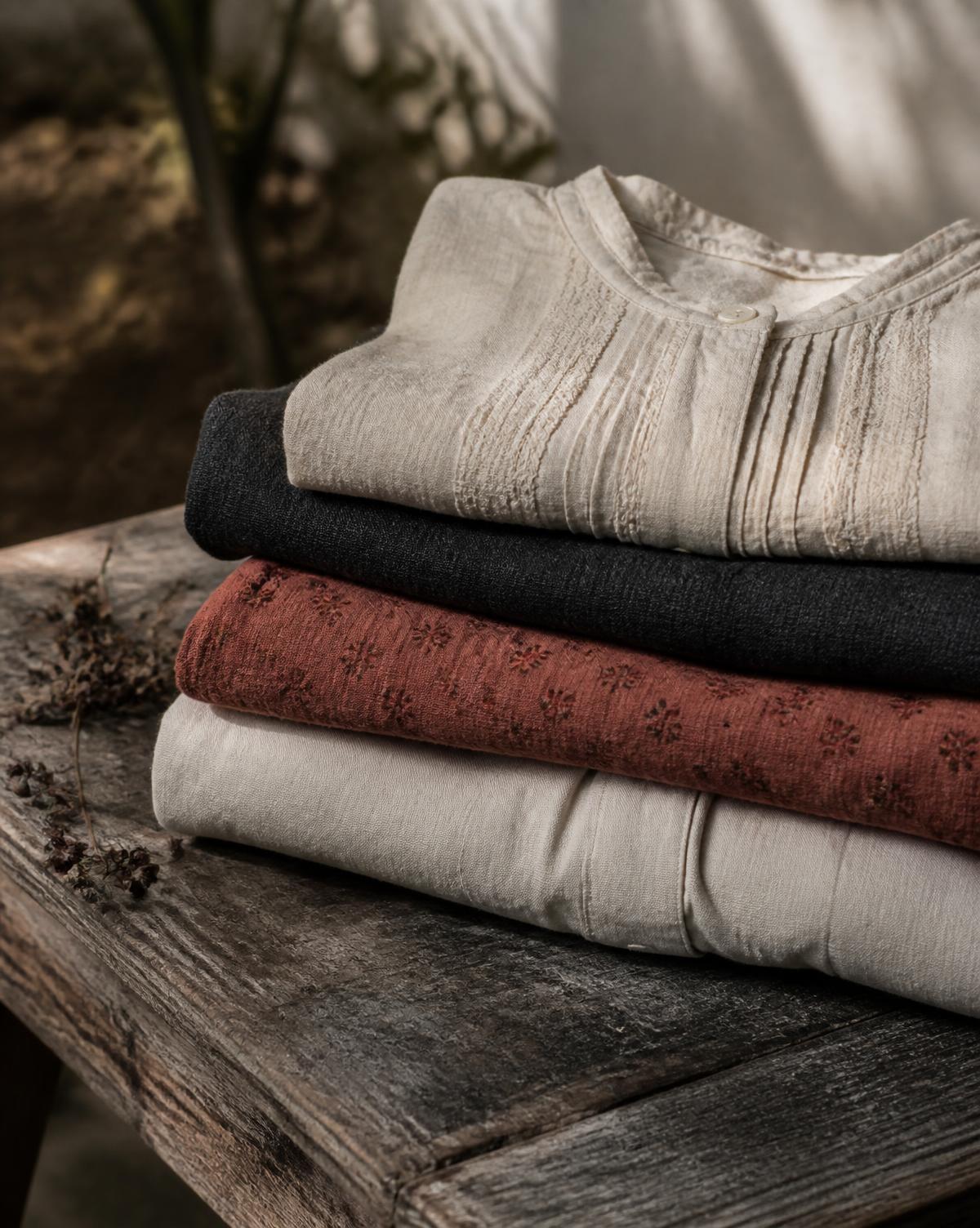 Folded secondhand garments stacked on a weathered wooden table